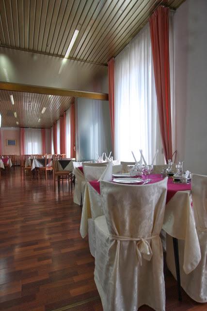 Restauracja z udekorowanymi stołami, białymi krzesłami i różowymi zasłonami.