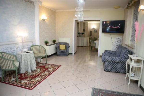 Elegancki salon z fotelami, stołem, dywanem i telewizorem na ścianie.