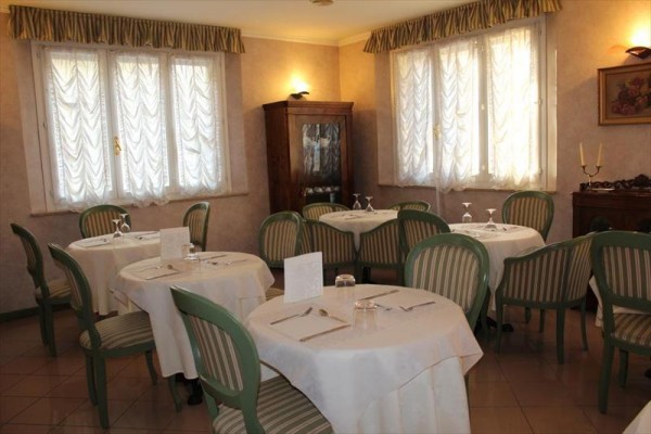 Elegancka restauracja z okrągłymi stolikami i zielonymi krzesłami.