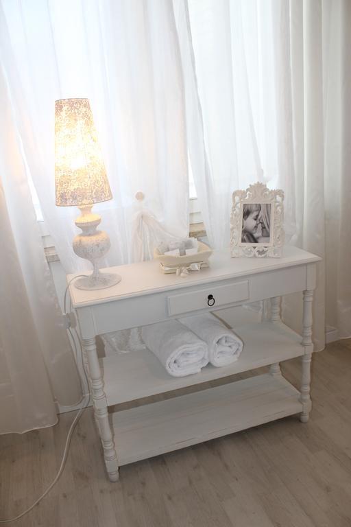 Mały biały stolik z lampą, świecami i ręcznikami przed zasłonami.  