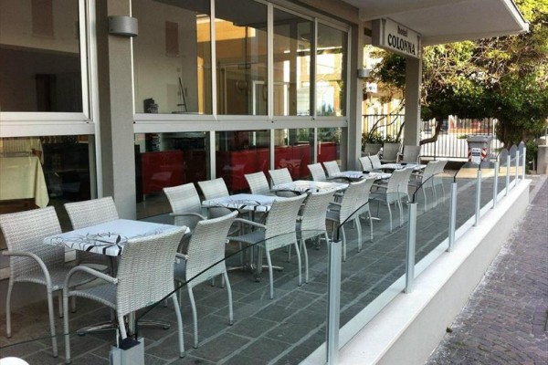Zewnętrzny taras restauracyjny z kilkoma stolikami i krzesłami.
