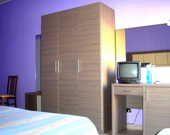 Pokój z fioletowymi ścianami, szafą, telewizorem na stole i krzesłem.