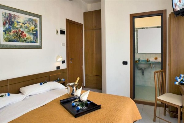 Przytulnie urządzony pokój hotelowy z podwójnym łóżkiem i przylegającą łazienką.