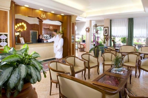 Recepcja hotelu z wygodnym miejscem do siedzenia i gośćmi przy ladzie.
