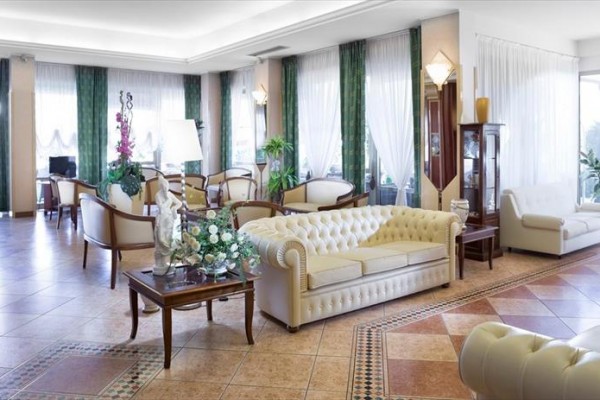 Eleganckie lobby hotelowe z białymi sofami i zielonymi zasłonami.