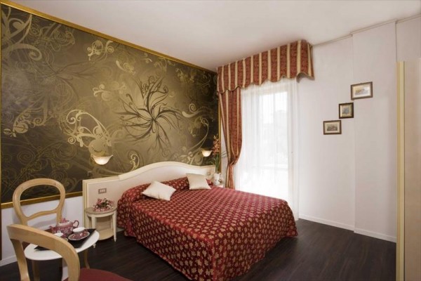 Elegancki pokój hotelowy z podwójnym łóżkiem i wyrazistą złotą tapetą.
