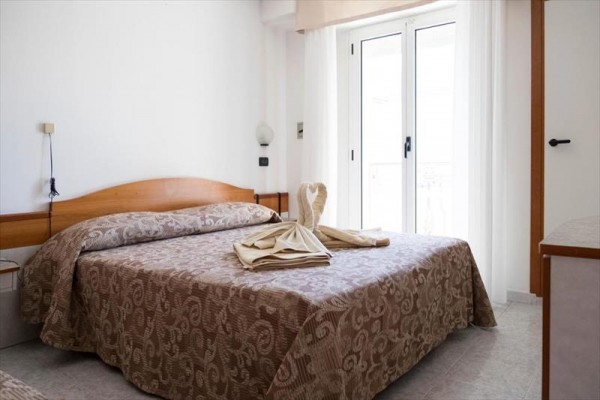 Pokój hotelowy z łóżkiem małżeńskim, na którym jest dekoracja z ręczników w kształcie łabędzia.