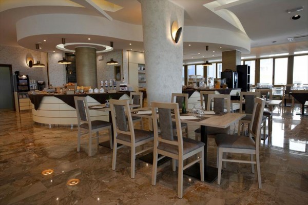 Nowoczesna restauracja z drewnianymi stołami i krzesłami na błyszczącej podłodze.
