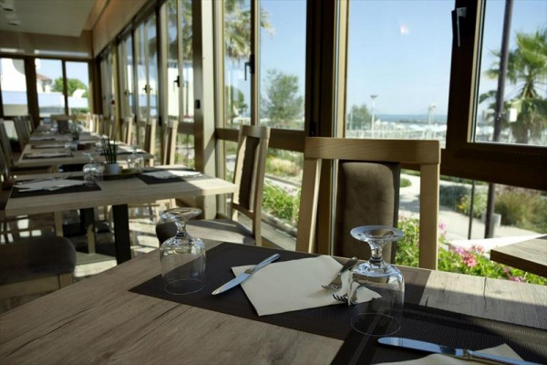 Restauracja z nakrytymi stołami i widokiem na ogród za oknami.