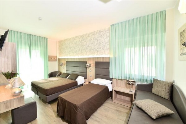 Pokój hotelowy z trzema łóżkami, biurkiem i nowoczesnym, dekoracyjnym wnętrzem.
