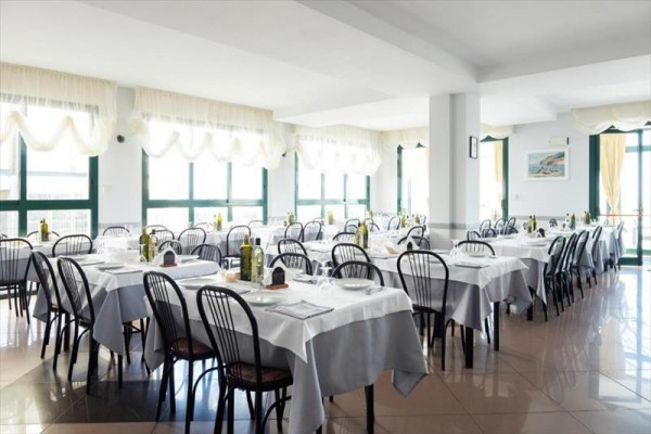 Przestronna restauracja z nakrytymi stołami i krzesłami wokół.