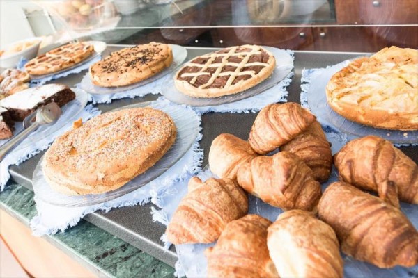 Różne rodzaje pieczywa i ciast wystawione na ladzie.
