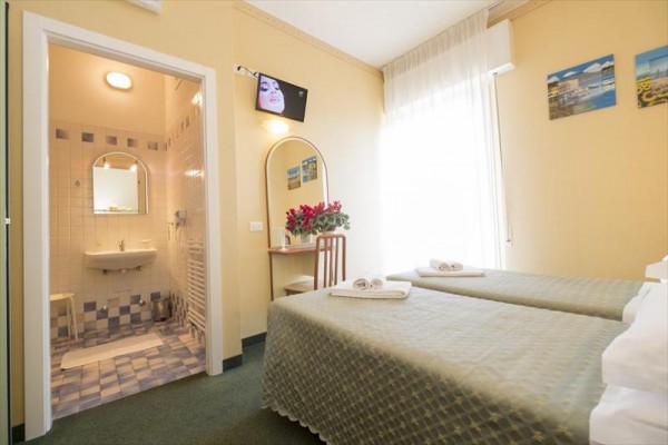 Pokój hotelowy z dwoma pojedynczymi łóżkami i łazienką.
