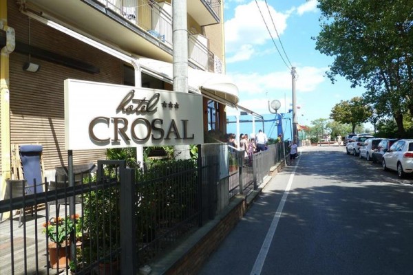 Znak hotelu Crosal przy drodze z samochodami i drzewami.