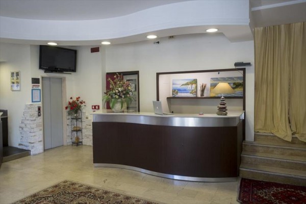 Recepcja hotelowa z ladą, kwiatami i lampą.