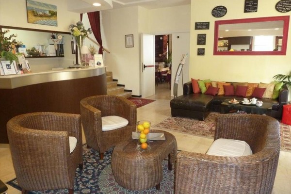 Recepcja hotelowa z rattanowymi fotelami i sofą z poduszkami.