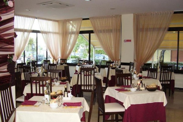 Restauracja z elegancko nakrytymi stołami i dużymi oknami.
