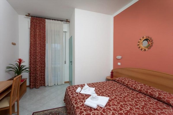 Pokój hotelowy z czerwoną ścianą, łóżkiem małżeńskim i biurkiem.