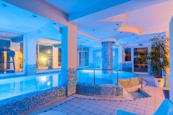 Wnętrze centrum wellness z basenem oświetlone niebieskim światłem.