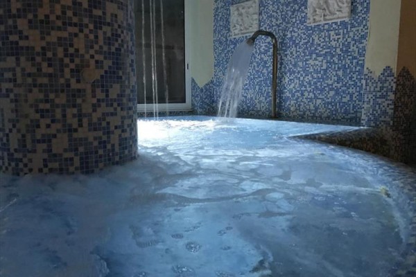 Wnętrze spa z mozaikową okładziną i wodospadem.