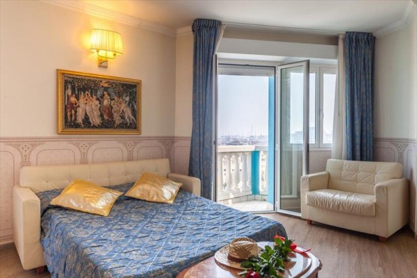 Pokój z sofą, fotelem i otwartymi drzwiami na balkon z widokiem.