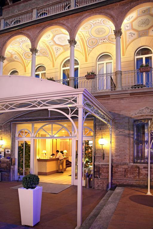 Wejście do eleganckiego hotelu z oświetloną aleją i sklepionym sufitem.