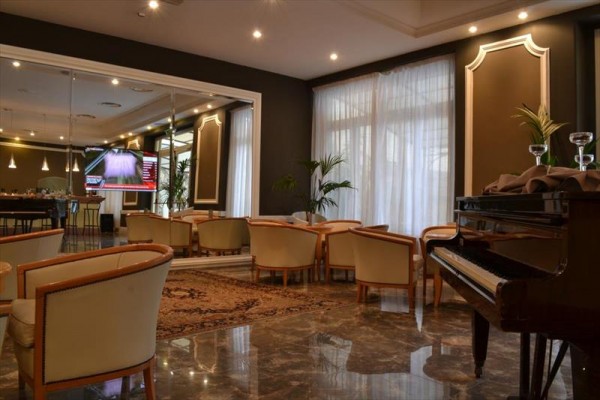 Elegancki salon hotelowy z fortepianem, nowoczesnymi meblami i dużym lustrem.