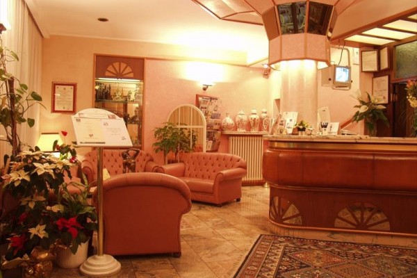 Lobby z różowymi sofami i drewnianą ladą recepcyjną.