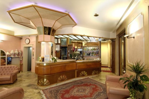 Recepcja hotelu z barem i skórzanymi sofami.