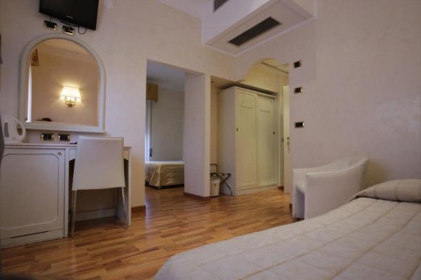 Nowoczesny pokój hotelowy z jasnymi meblami i drewnianą podłogą.