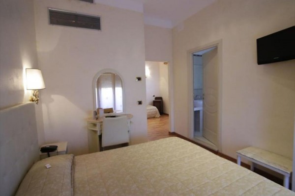 Pokój hotelowy z podwójnym łóżkiem, lustrem na toaletce i przylegającą łazienką.