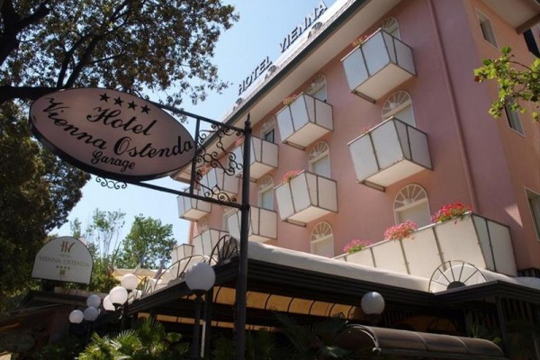 Różowy hotel z balkonami i tabliczką wskazującą pięciogwiazdkowy Hotel Vienna Ostenda.