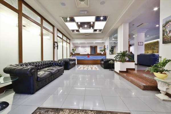 Nowoczesna recepcja hotelowa z skórzanymi sofami i kwiatami.