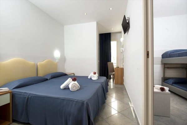 Pokój hotelowy z podwójnym łóżkiem, łóżkiem piętrowym i niebieską pościelą.