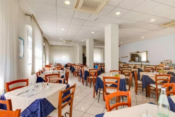 Restauracja z drewnianymi krzesłami, białymi obrusami i niebieskimi bieżnikami.