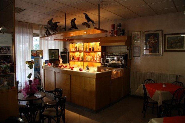 Bar z napojami i ekspresem do kawy w przytulnej restauracji z ozdobnymi figurkami na półce.