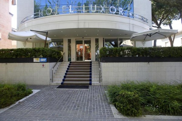 Wejście do nowoczesnego hotelu z tarasem i parasolami.