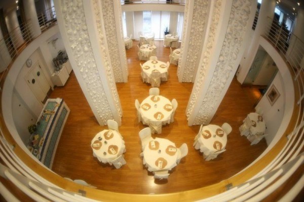 Widok z góry na elegancko nakrytą restaurację z okrągłymi stołami i zdobionymi filarami.