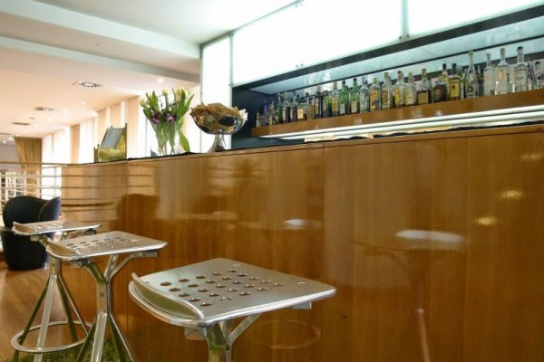 Nowoczesny bar z drewnianym blatem, kwiatami i butelkami alkoholu.