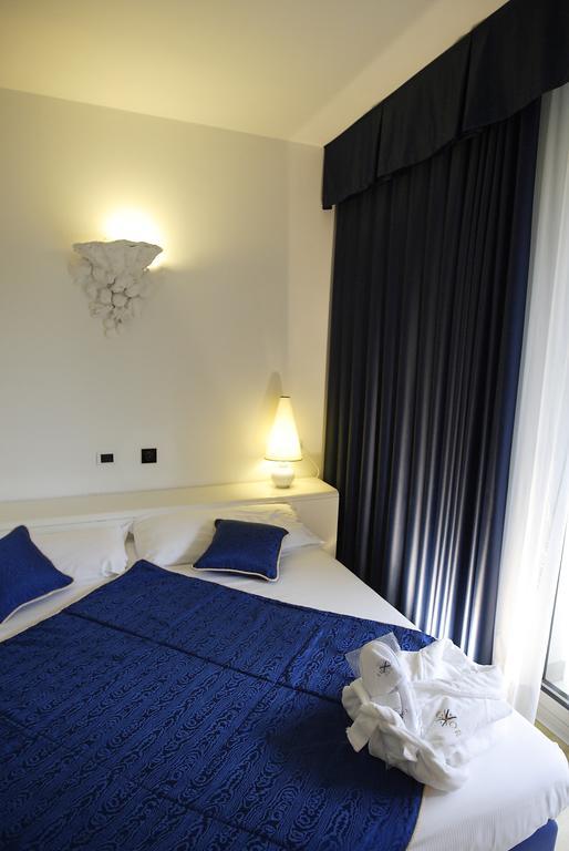 Łóżko dwuosobowe z niebieską narzutą i poduszkami w pokoju hotelowym.