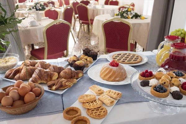 Bufet śniadaniowy z pieczywem, owocami i sokami w hotelowej jadalni.
