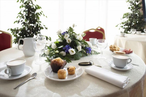 Luksusowo nakryty stół z kwiatową dekoracją, kawą i muffinkami.