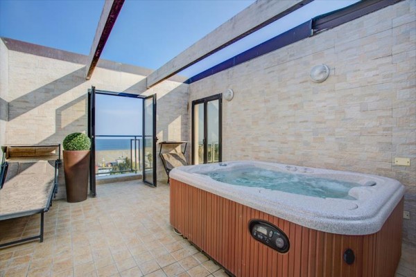 Taras z jacuzzi i widokiem na morze.