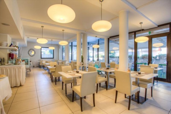 Jasna nowoczesna restauracja z białymi stołami i krzesłami.