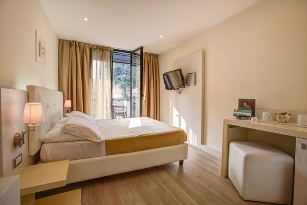 Nowoczesny pokój hotelowy z podwójnym łóżkiem, telewizorem i balkonem.