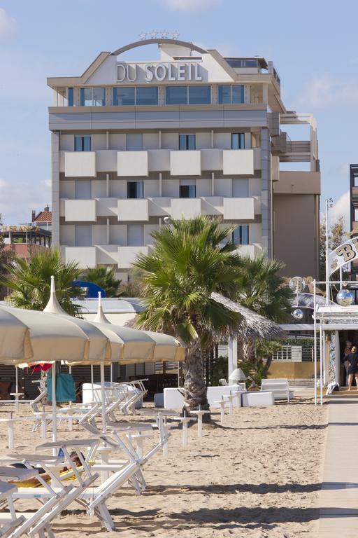 Widok plaży z palmami i leżakami przed hotelem DU SOLEIL.