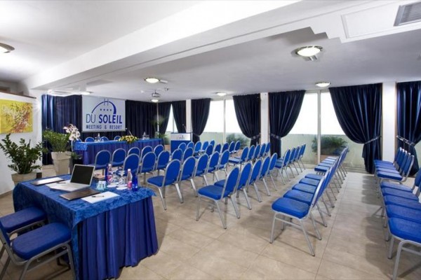 Sala konferencyjna z niebieskimi krzesłami i stołem pokrytym niebieskim obrusem.