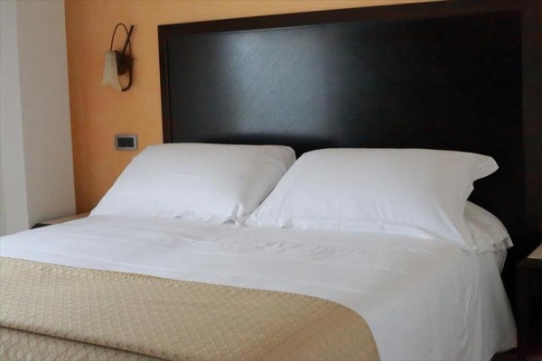 Łóżko z białą pościelą i poduszkami w pokoju hotelowym.