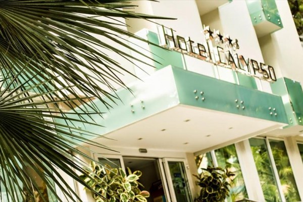 Wejście do hotelu Calypso z zielonym napisem i czterema gwiazdkami na fasadzie.