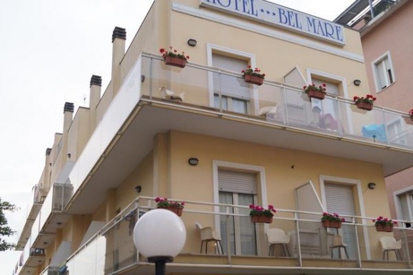 Trzypiętrowy budynek hotelu Bel Mare z balkonem ozdobionym kwiatami.